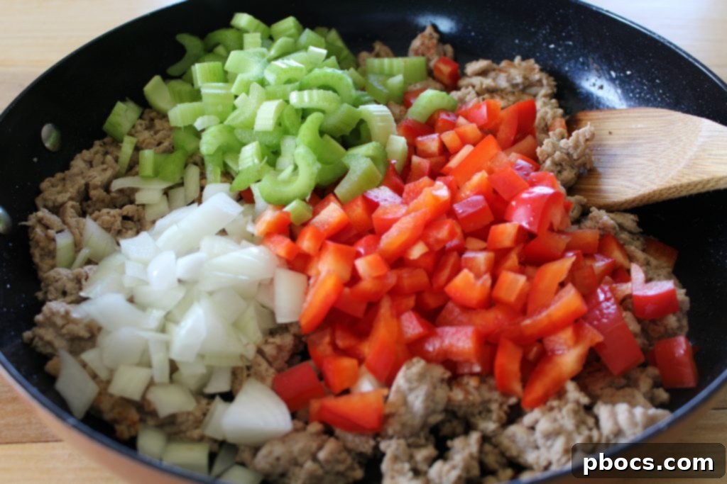 Sautéing diced onions, celery, and bell pepper with browned ground meat