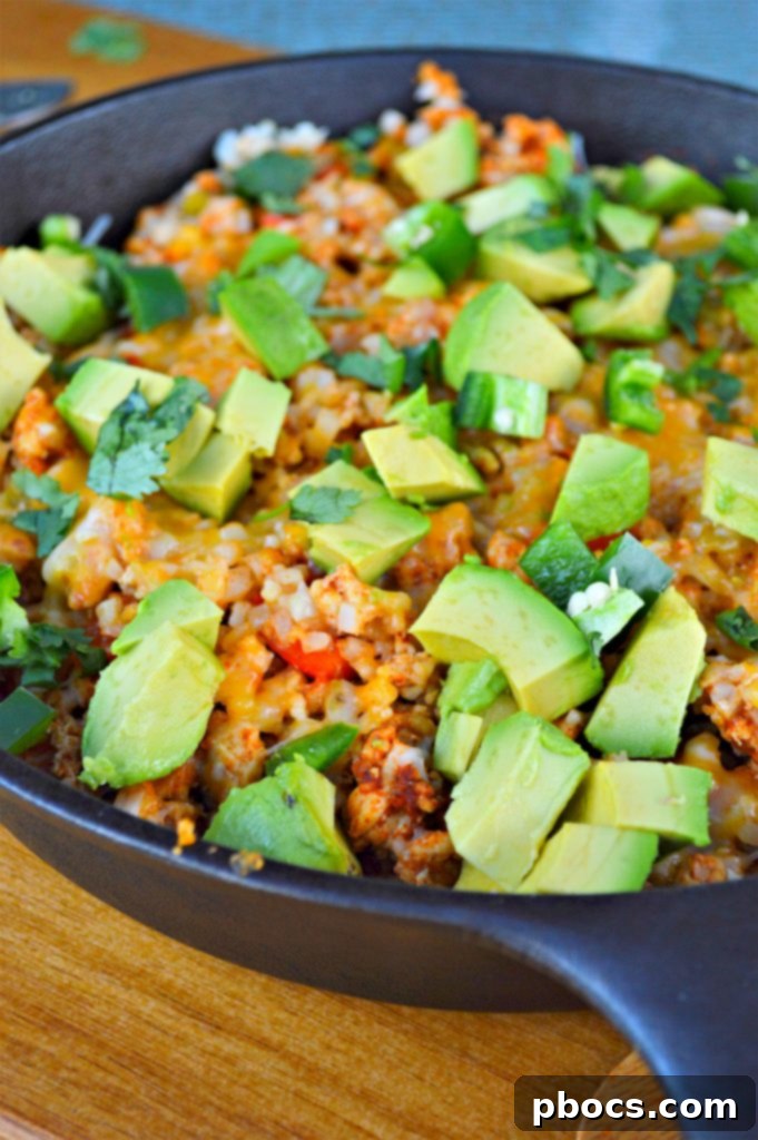A close-up of a serving of Keto Turkey Mexican Skillet, richly topped with fresh cilantro, avocado, and sour cream, showcasing its delicious appeal.