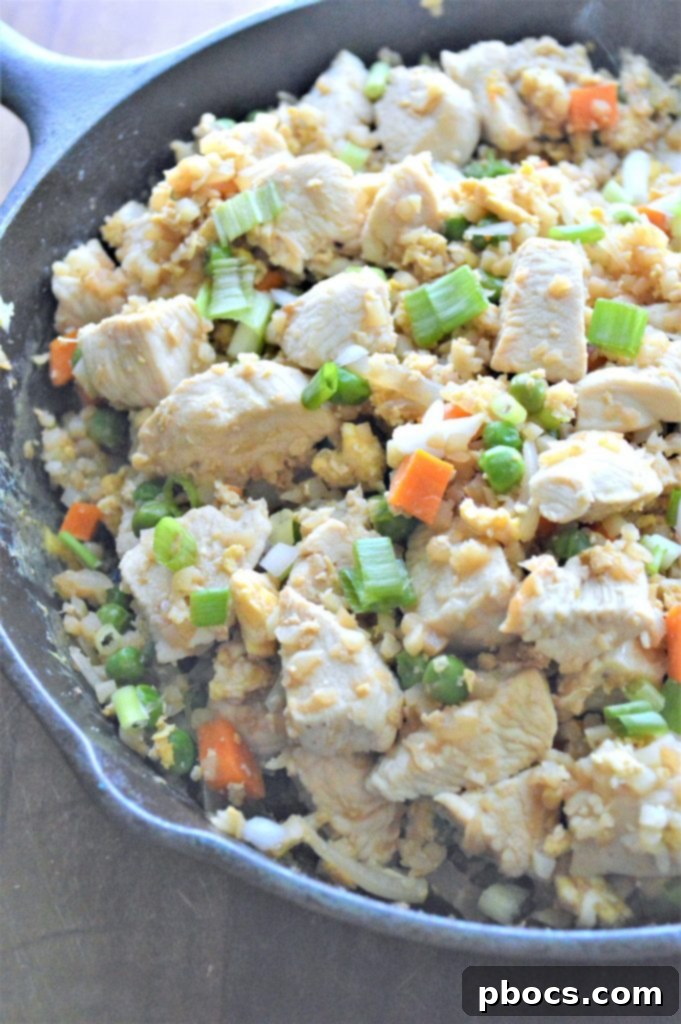 All ingredients combined in the skillet, including cauliflower rice and chicken