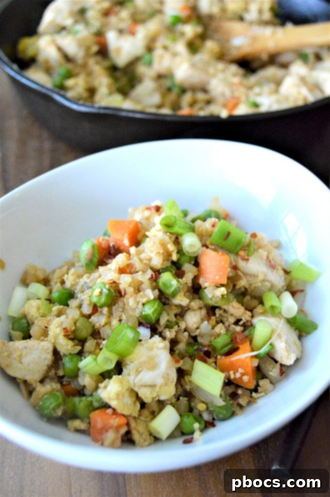 A serving of Keto Cauliflower Chicken Fried Rice in a bowl, garnished with green onions