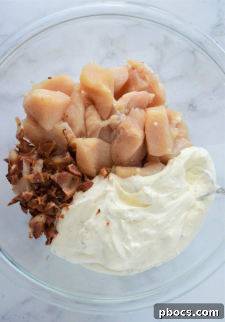 Adding chicken and half of the bacon to the creamy mixture