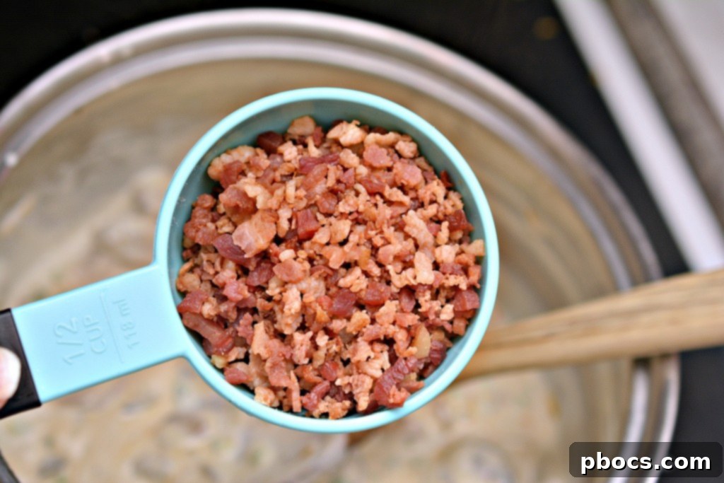 Spicy Keto Jalapeno Popper Green Bean Casserole 11 Step-by-step photo showing bacon pieces and cheddar cheese being stirred into the creamy sauce for the green bean casserole