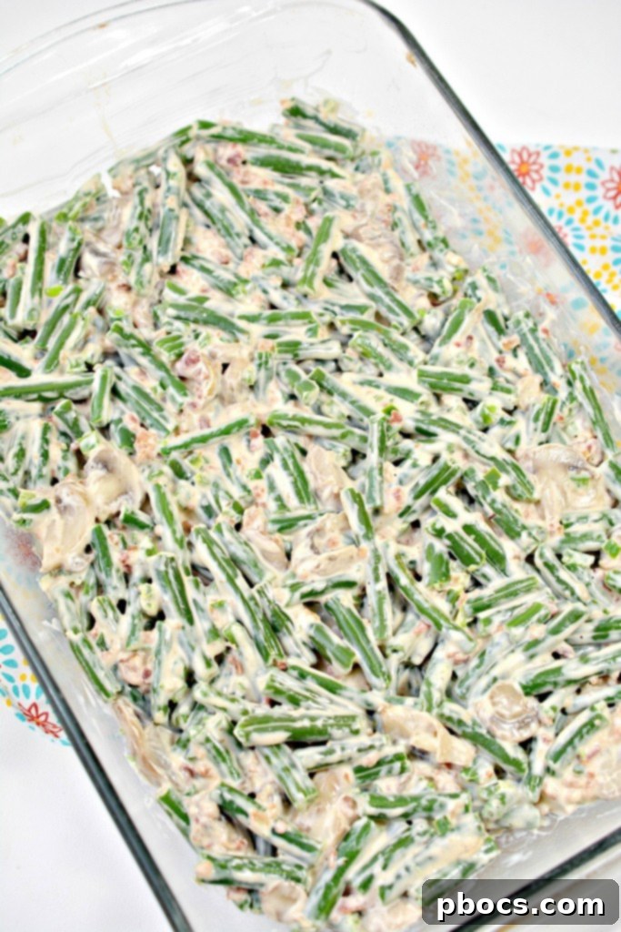 Spicy Keto Jalapeno Popper Green Bean Casserole 12 Step-by-step photo of the creamy green bean mixture being poured into a baking dish for the casserole