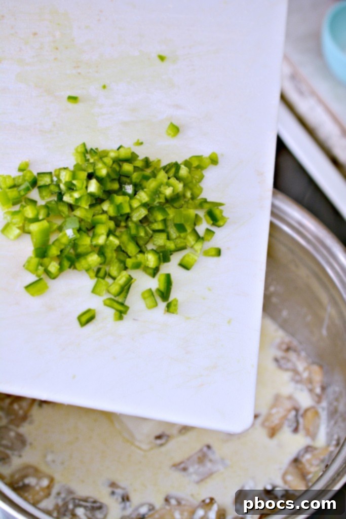 Spicy Keto Jalapeno Popper Green Bean Casserole 9 Step-by-step photo showing cream cheese, heavy cream, and jalapeno being added to the sautéed mushrooms in a saucepan