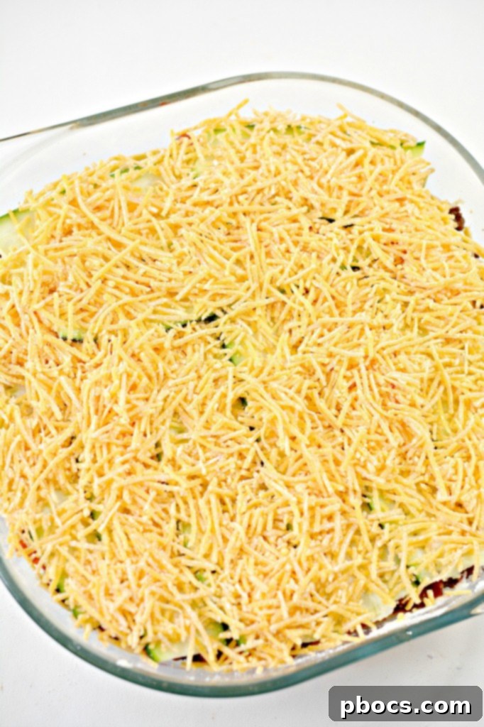 Layers of zucchini, ricotta, beef, and salsa in the baking dish.