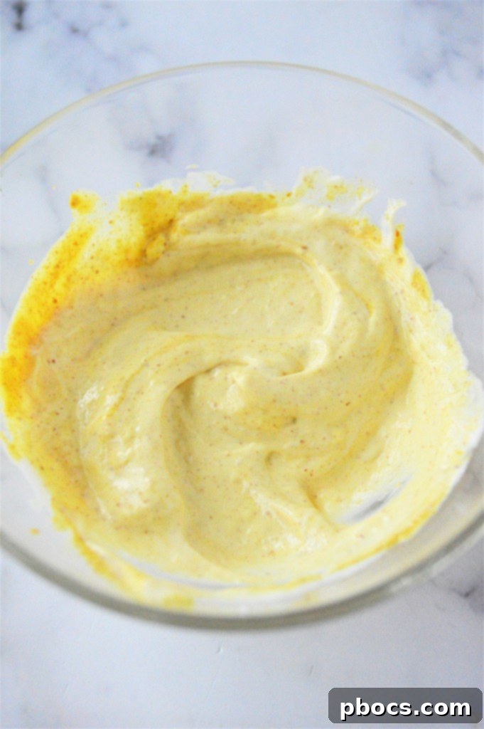 Step 3: Whisking together the mayonnaise, mustard, and hot sauce for the dressing.