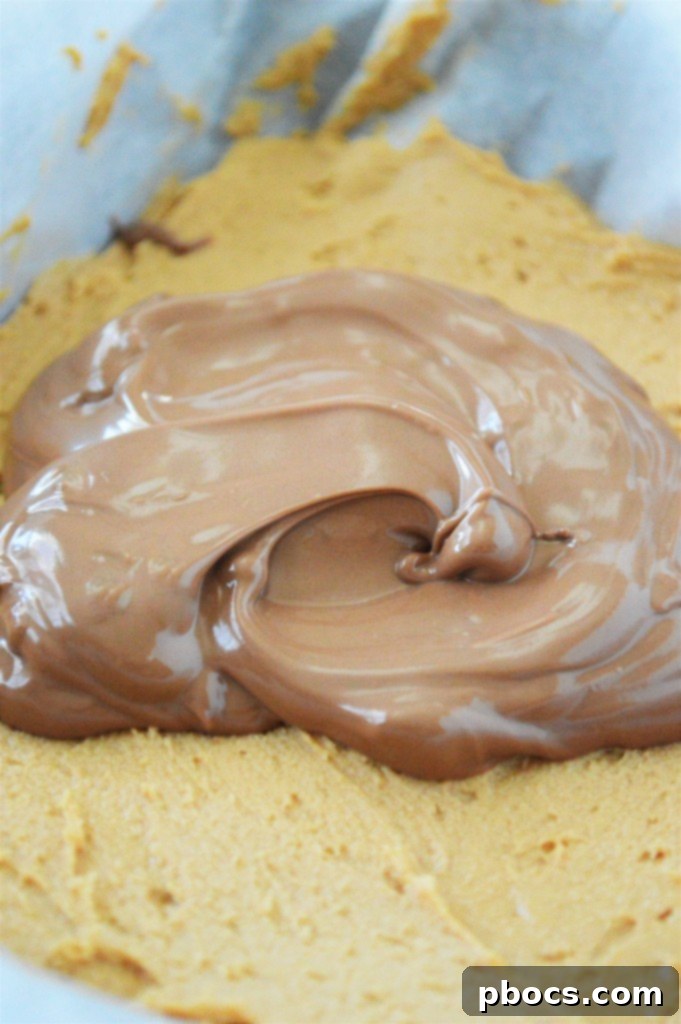 Effortless Keto Chocolate Peanut Butter Bars 12 Step 5: Pouring melted chocolate over the set peanut butter layer to create the top coating.