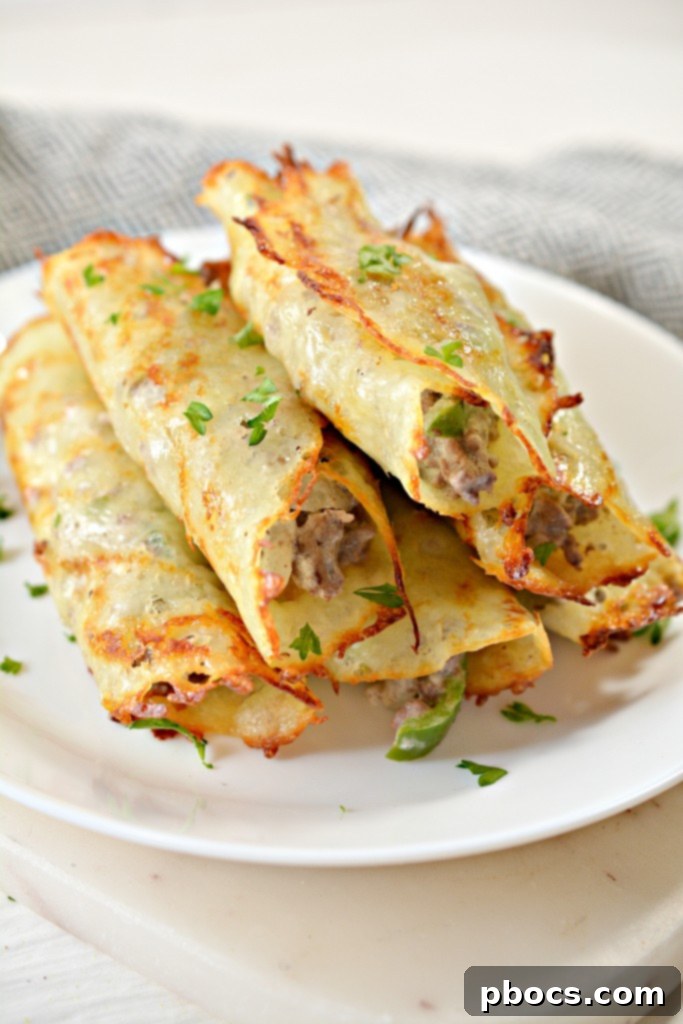 Several perfectly formed Keto Philly Cheesesteak Roll Ups arranged on a rustic wooden board, ready to serve