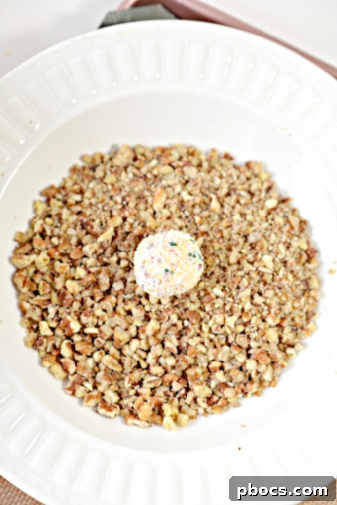 Cheese balls being rolled in finely chopped pecans