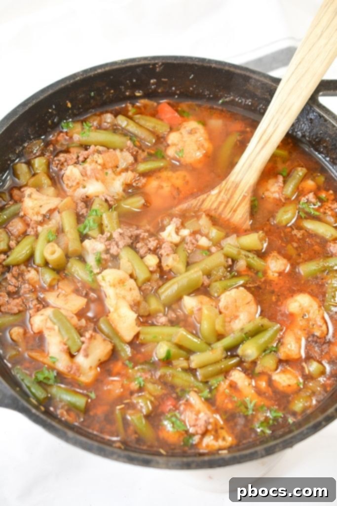 Stirring the Low Carb Vegetable Beef Soup with a Wooden Spoon