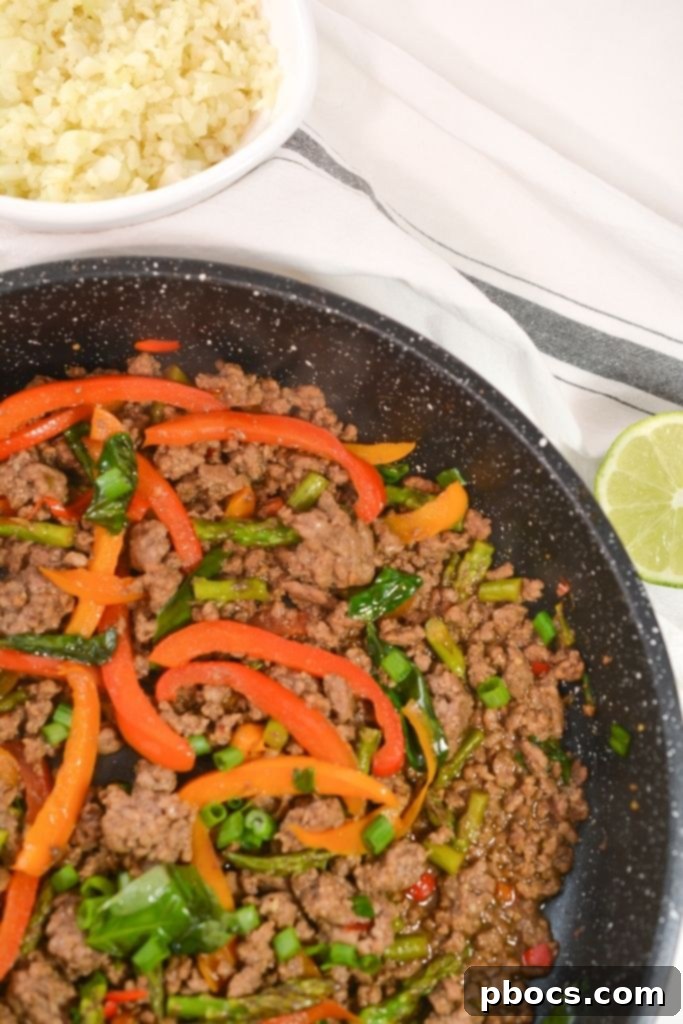 A skillet of Thai Basil Beef with a spatula
