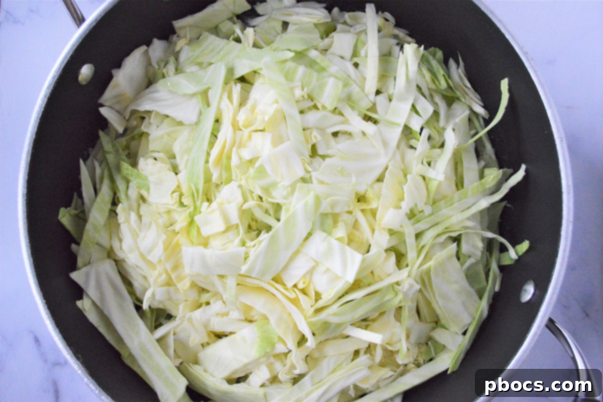 Adding sliced cabbage to the skillet with butter and garlic