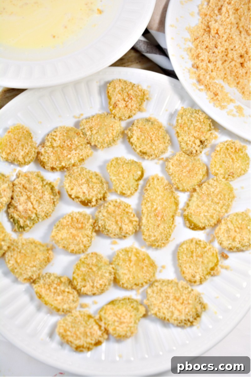 Dipping pickle chips in egg and then crumbs