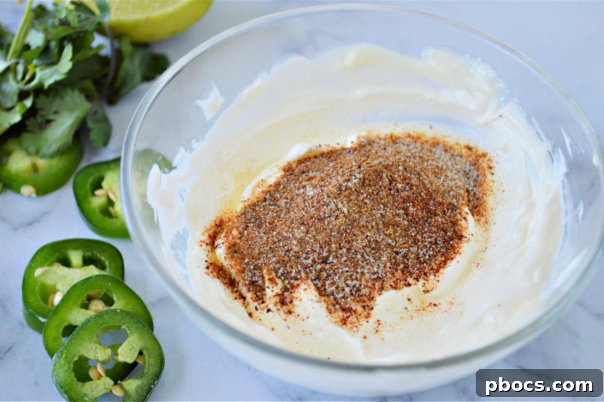 Mixing bowl with mayonnaise, sour cream, garlic salt, chili powder, cumin, and lime juice for the creamy dressing.
