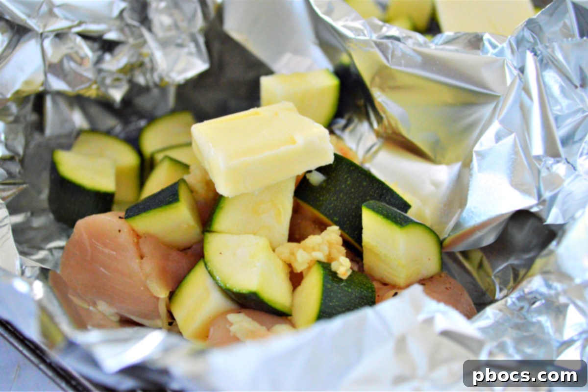 Step 5: Adding garlic and butter to the chicken and zucchini in foil