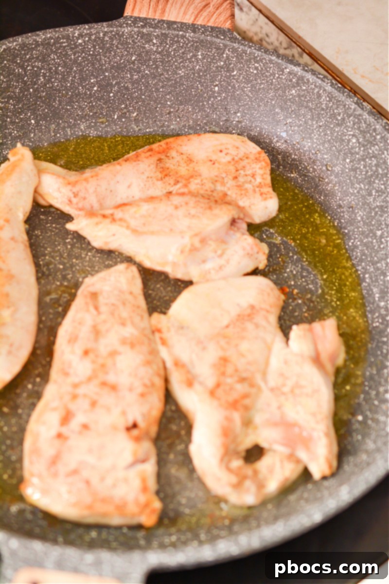 Searing chicken breasts in a hot skillet, golden-brown and ready for the next step.