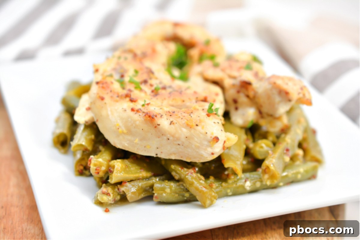 A serving of Keto Honey Mustard Chicken with green beans, garnished with fresh herbs.