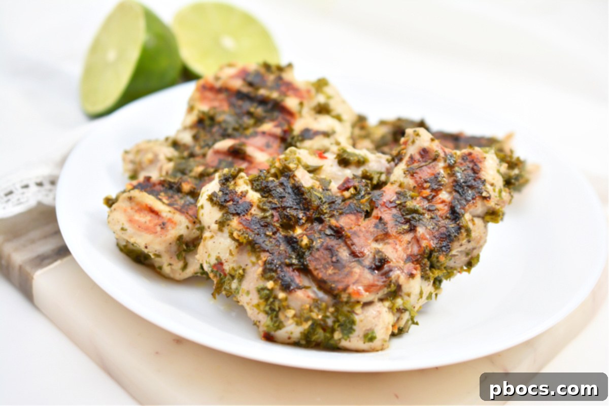 Hand whisking chimichurri sauce in a glass bowl, showing its vibrant green color