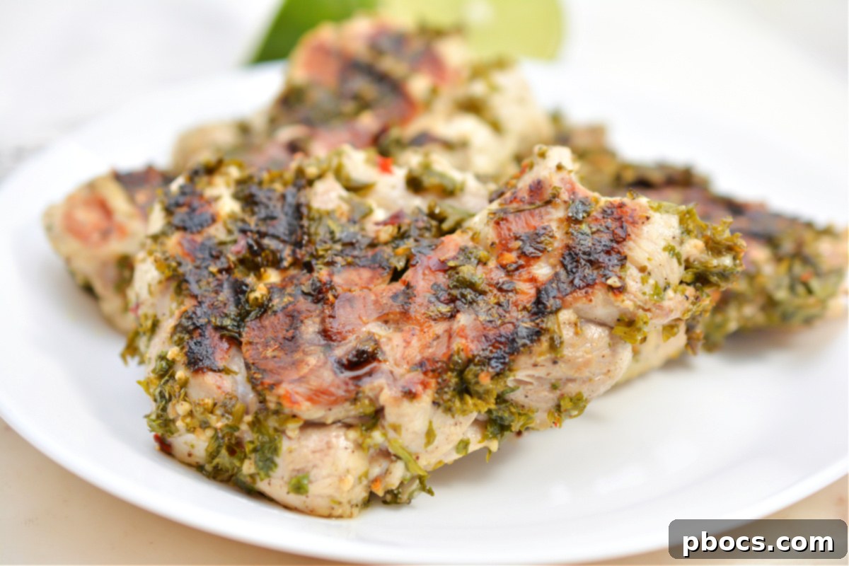 Chicken thighs marinating in chimichurri sauce in a bowl