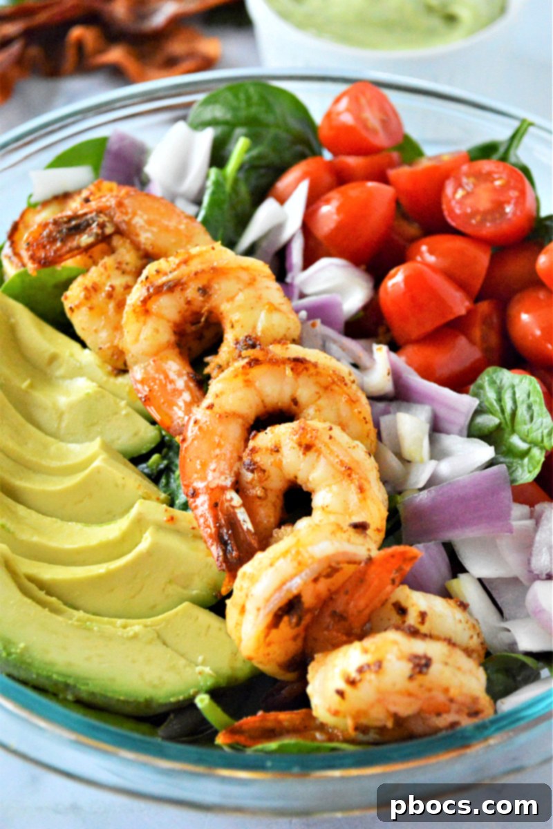 Step 7: Adding avocado slices to the shrimp and spinach salad.