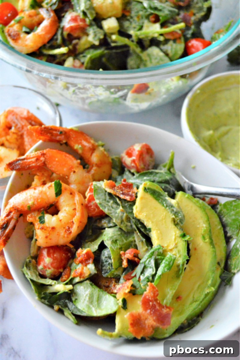 Close-up of fresh shrimp, avocado, and spinach salad ingredients arranged beautifully.