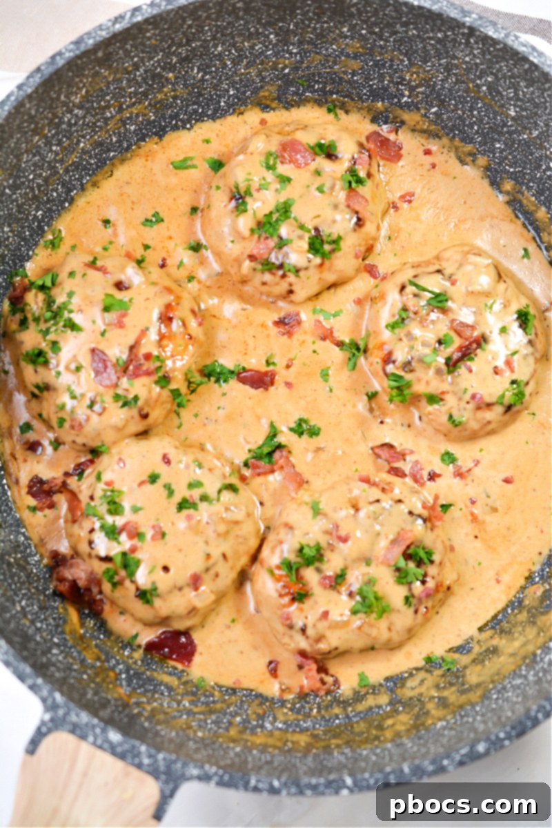 A single skillet filled with cooked Keto Cheddar Ranch Chicken Burgers smothered in BBQ Cream Sauce