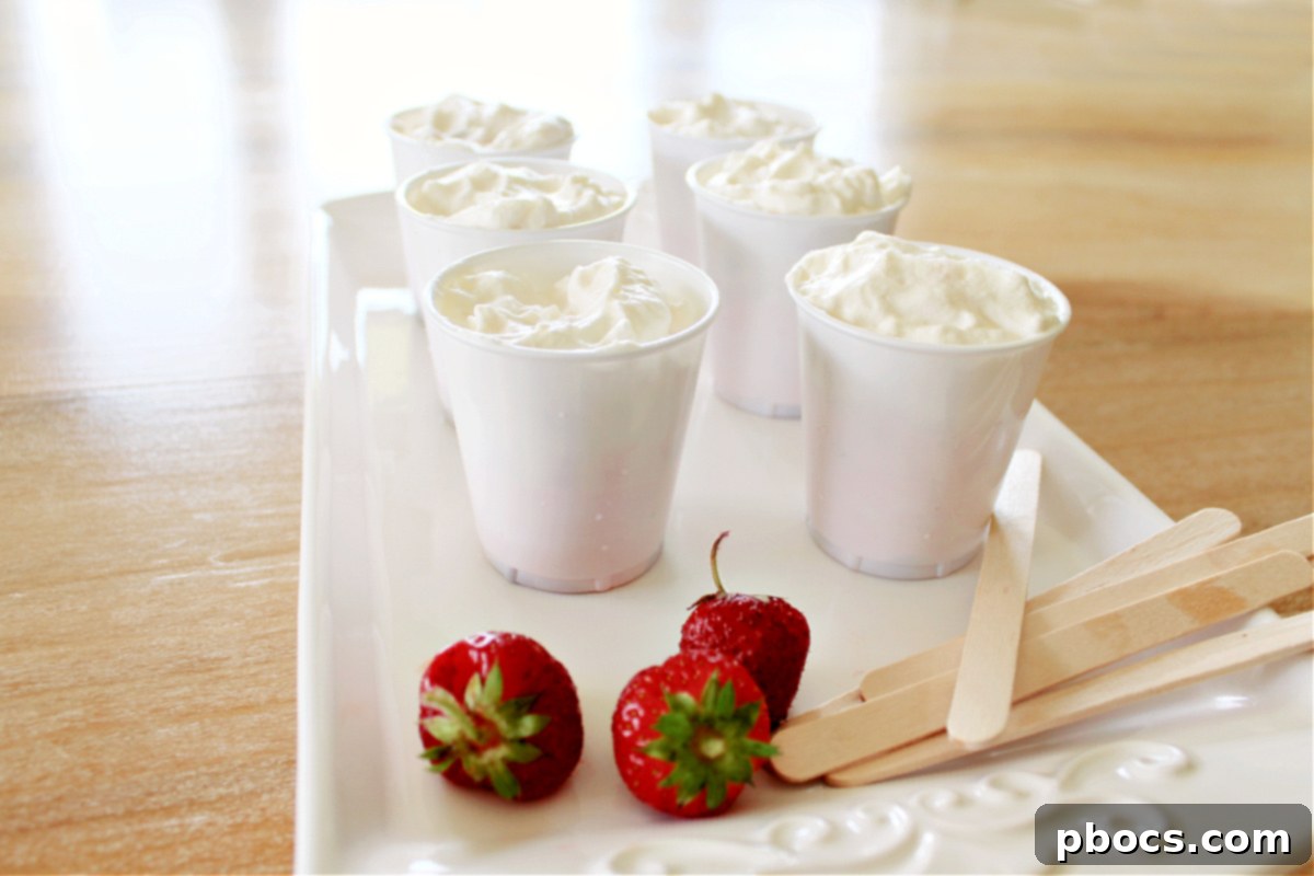 Layering pink and white mixtures in Dixie cups for Keto Popsicles