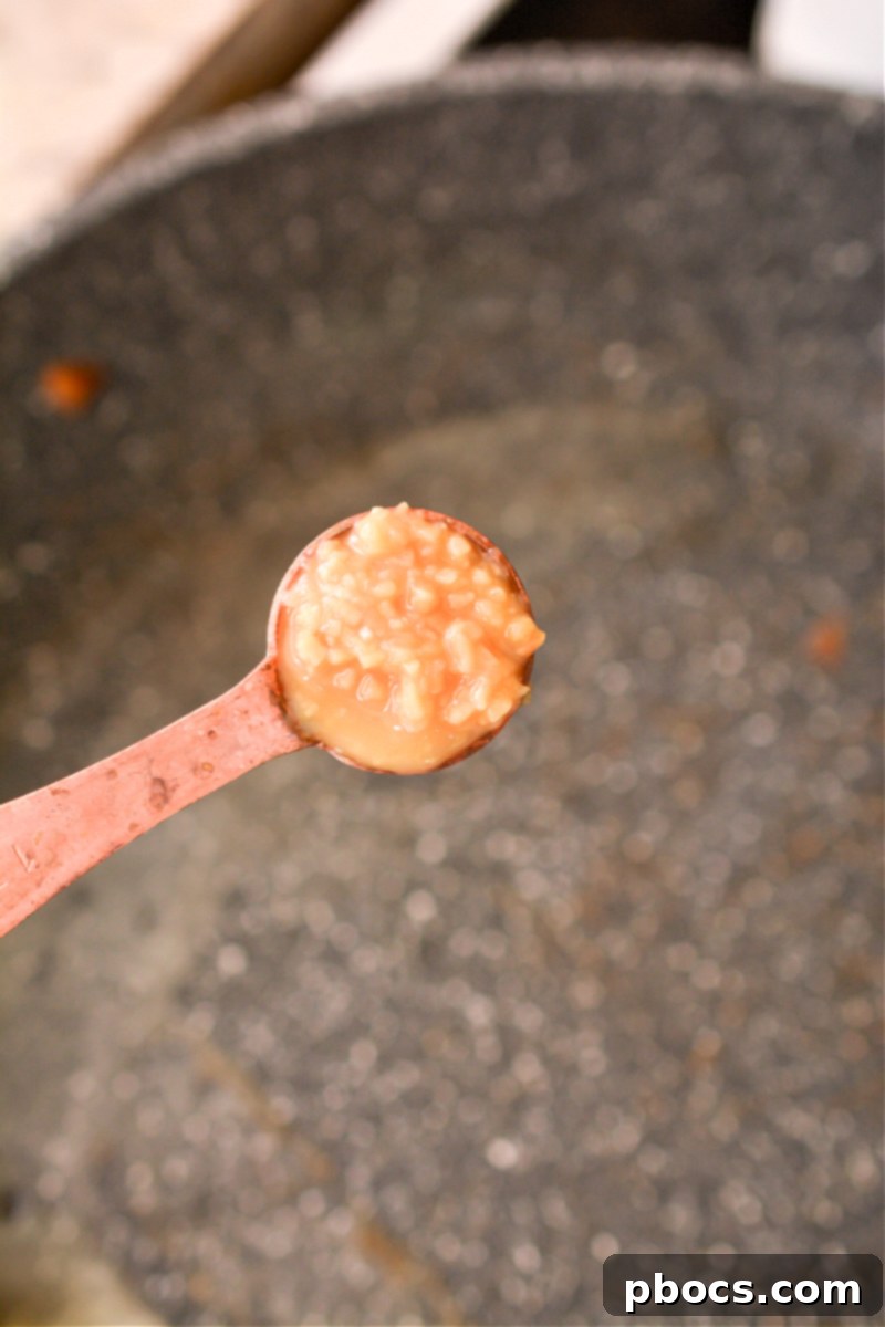 Comforting Keto Tuna Bake 18 Garlic being sautéed in butter in a skillet, releasing its aromatic fragrance.