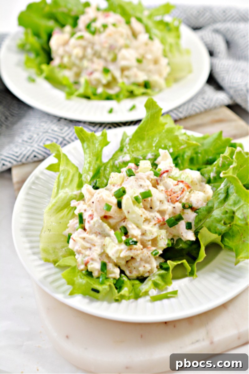 Hand mixing the creamy keto lobster salad ingredients in a bowl.