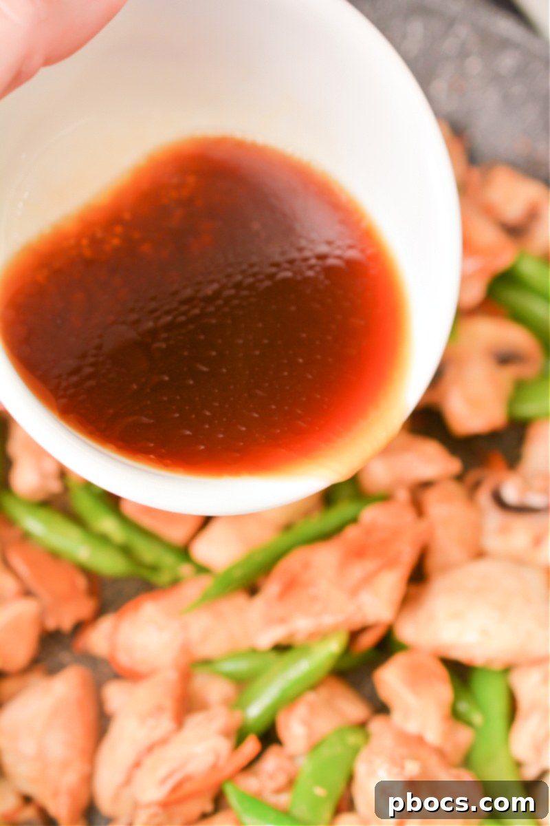 Keto Moo Goo Gai Pan Stir Fry 17 Step 9: Pouring sauce over chicken and veggies, stirring to combine.