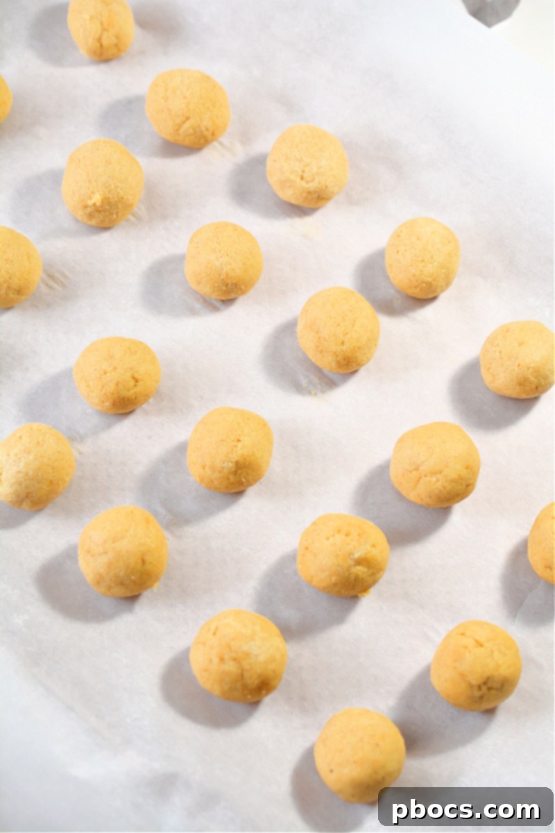 Hands rolling dough into small balls for donut holes