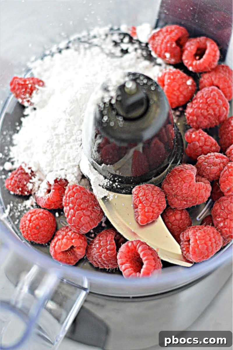 Blending fresh raspberries and sweetener in a food processor for sauce