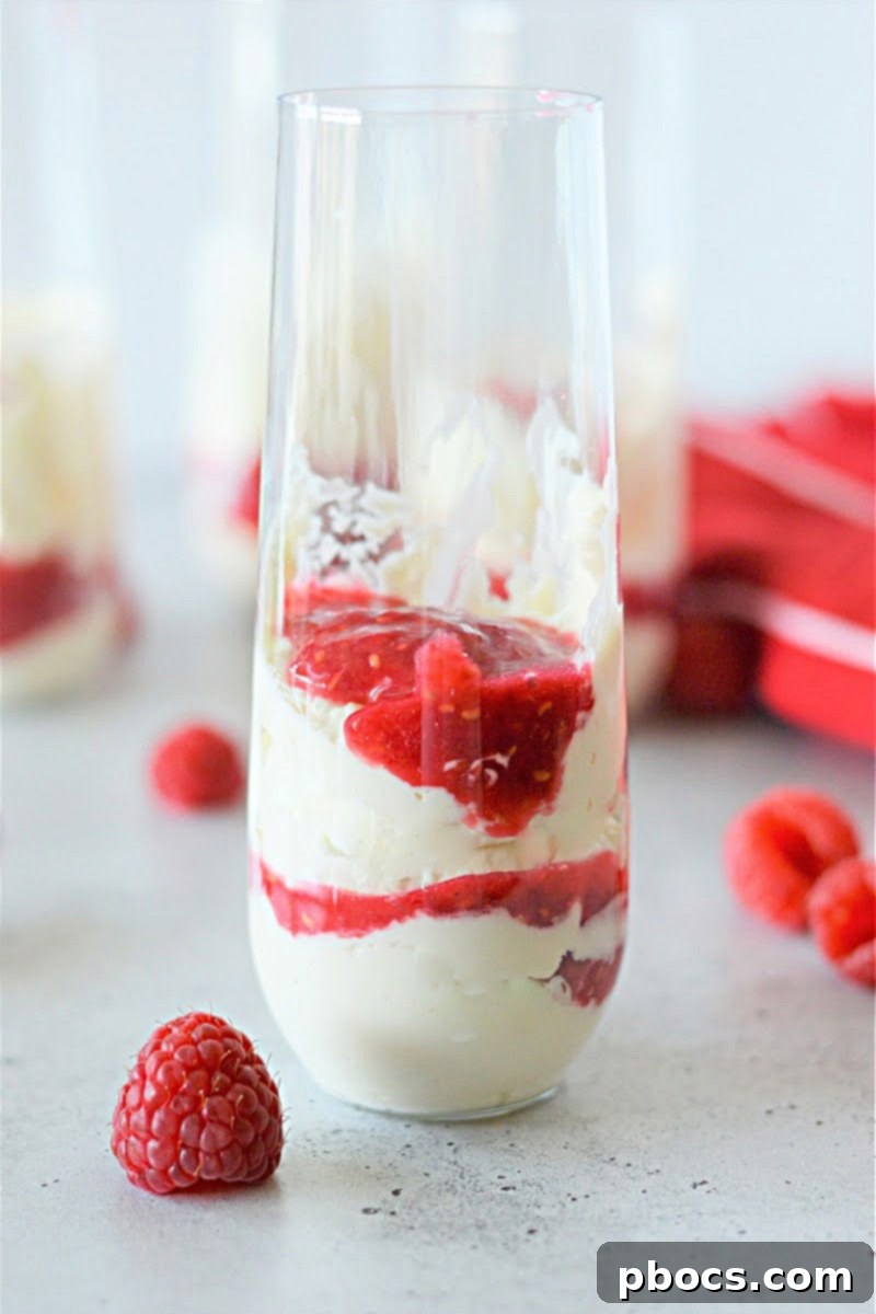Close-up of Keto Cheesecake Fluff topped with vibrant raspberry sauce in a glass