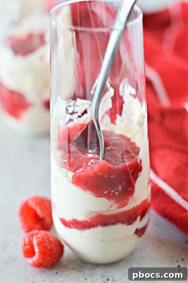 Keto Cheesecake Fluff with raspberry sauce in clear glasses on a white background