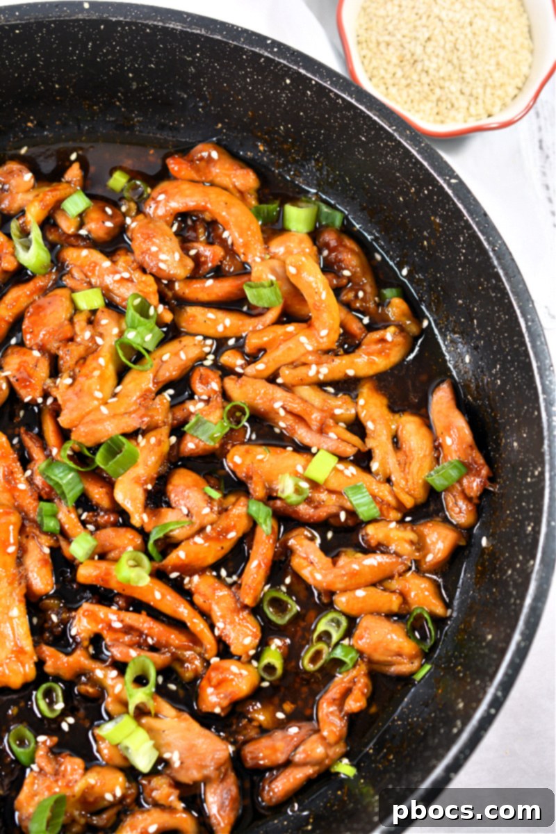 Sticky Keto Garlic Chicken served with cauliflower rice, garnished with green onions and sesame seeds.