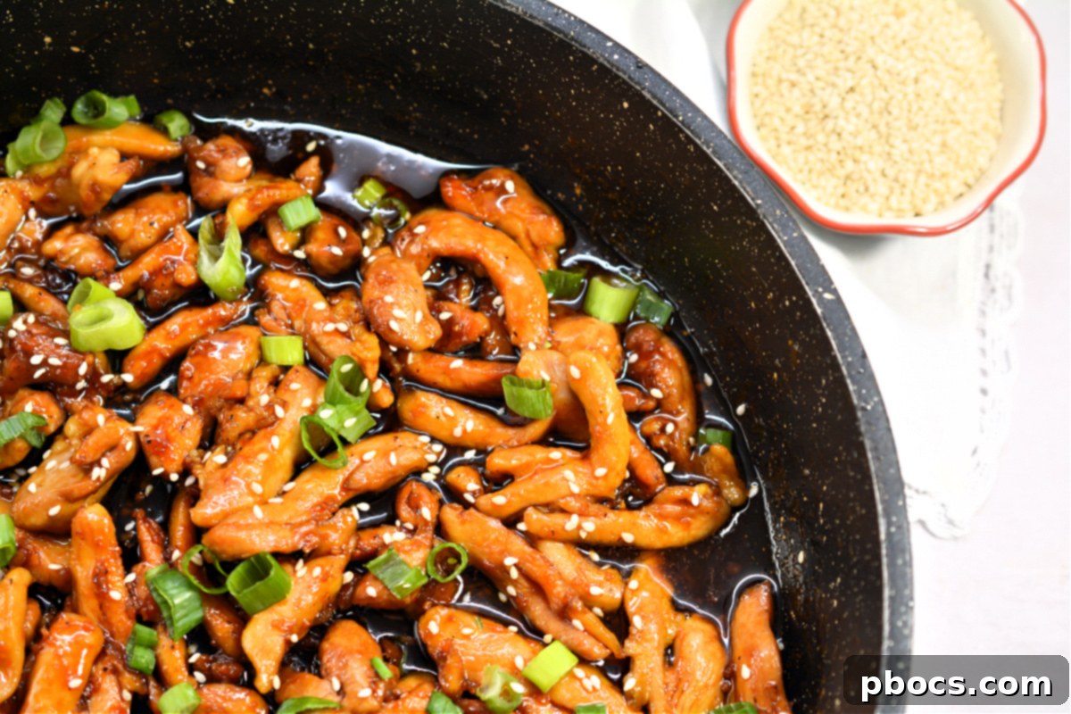 Close-up of Sticky Keto Garlic Chicken simmering in a thick, glossy sauce in a skillet.