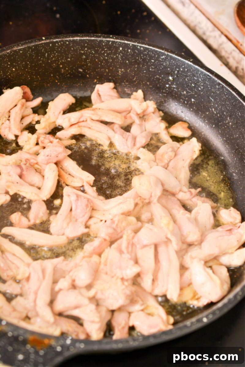 Sautéing boneless skinless chicken strips in olive oil in a hot skillet.