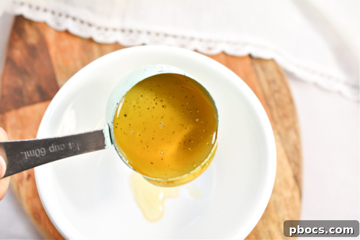 Whisking together the sauce ingredients: soy sauce, sugar-free honey, garlic, sriracha, ginger paste, and sesame oil.