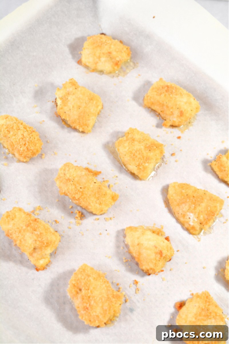 Keto Cordon Bleu Chicken Poppers 16 Baked chicken pieces on a baking sheet, golden brown and cooked.