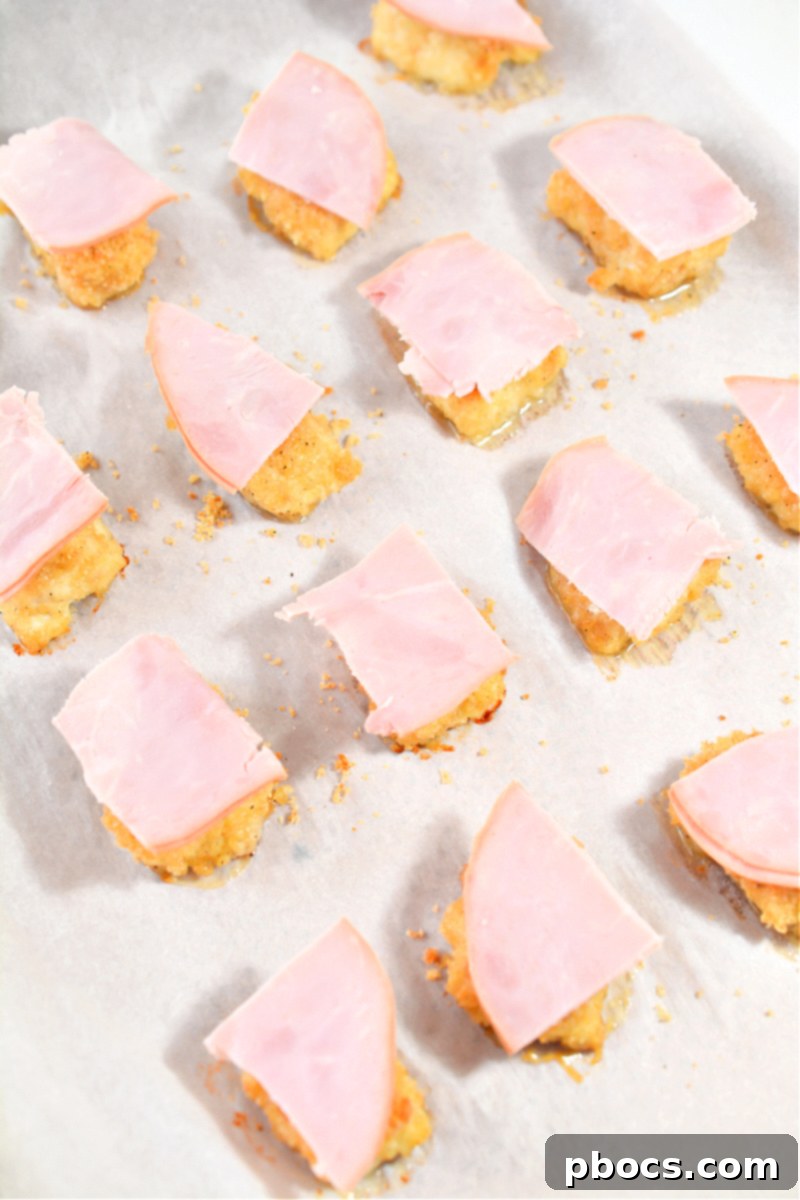 Keto Cordon Bleu Chicken Poppers 17 Topping baked chicken with ham squares.