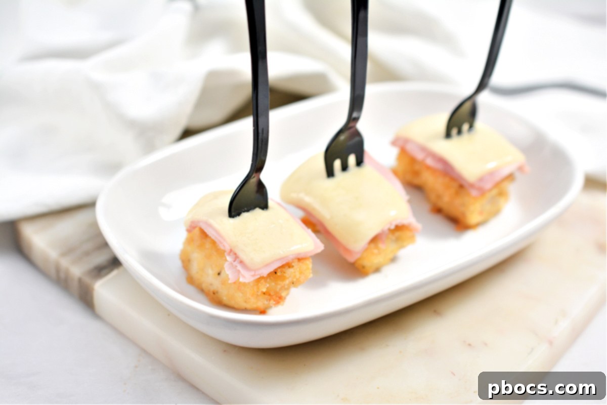 Keto Cordon Bleu Chicken Poppers 6 Keto Chicken Cordon Bleu Bites arranged elegantly on a platter with small forks, perfect for a party.