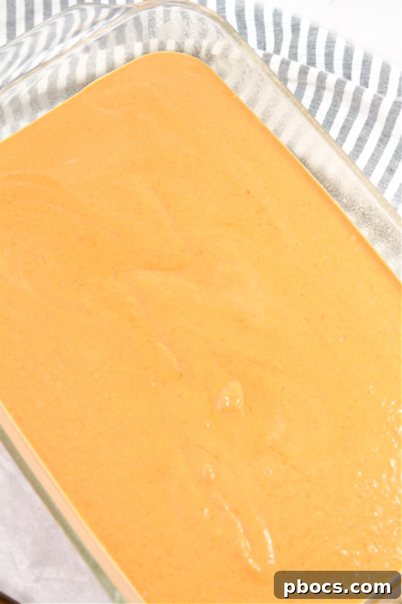 Pouring pumpkin batter into a greased baking dish for dump cake