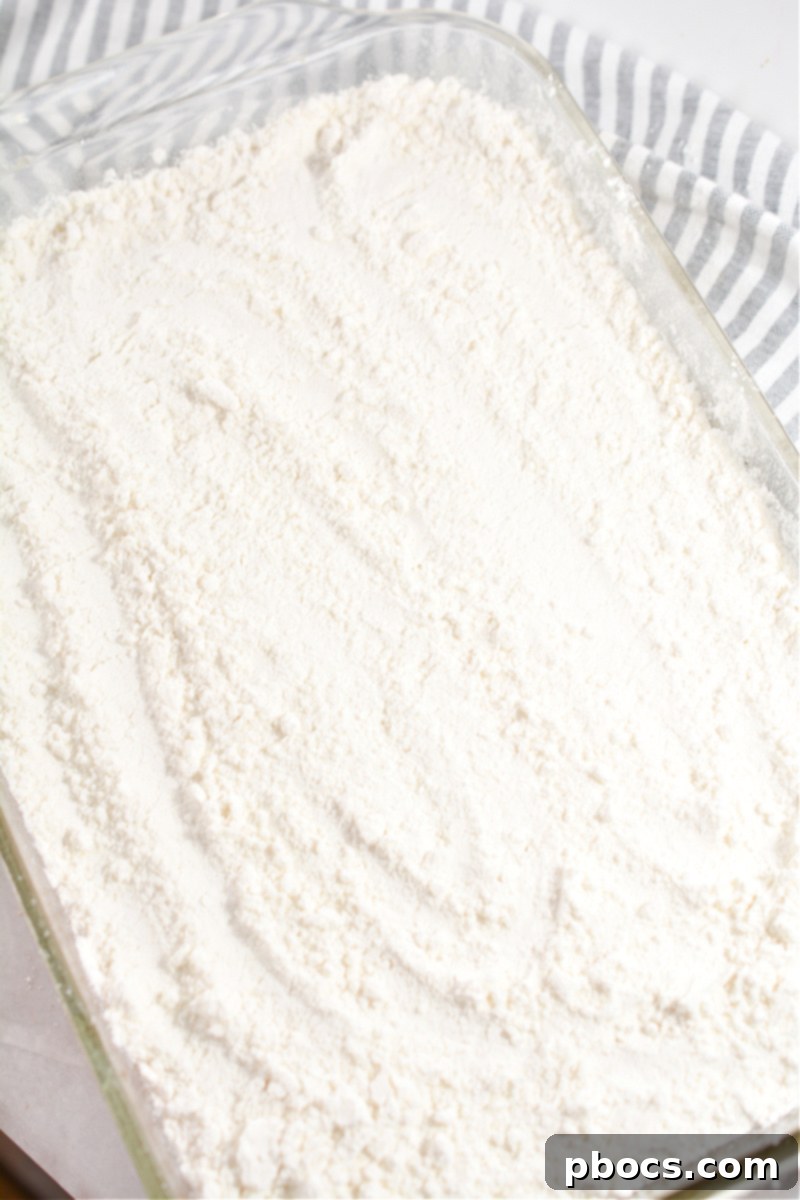 Sprinkling keto cake mix over pumpkin mixture for dump cake topping