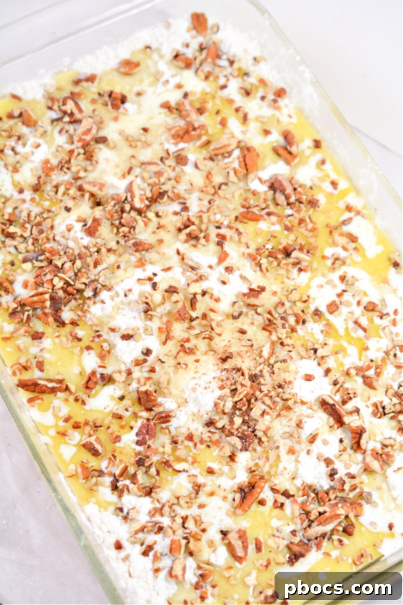 Sprinkling chopped pecans on top of the dump cake layers