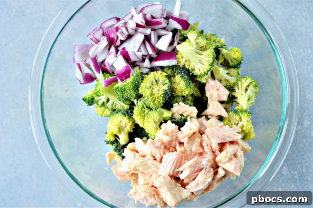 Mixing broccoli, red onion, and chicken for the salad