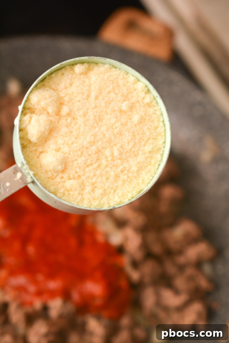 Adding minced garlic to the cooked meat mixture