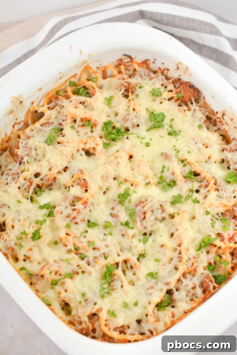 Topping Keto Baked Spaghetti with shredded mozzarella cheese