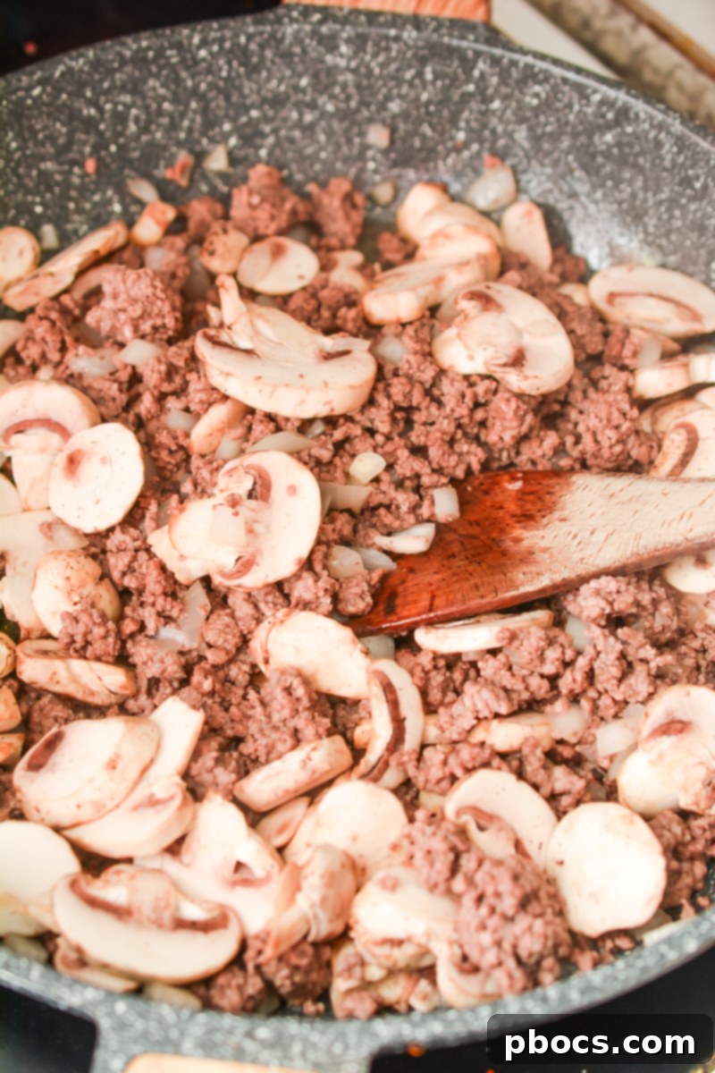Ultimate Cheesy Keto Beef, Spinach & Mushroom Feast 9 Ground beef and onions browning in a skillet for the casserole base.