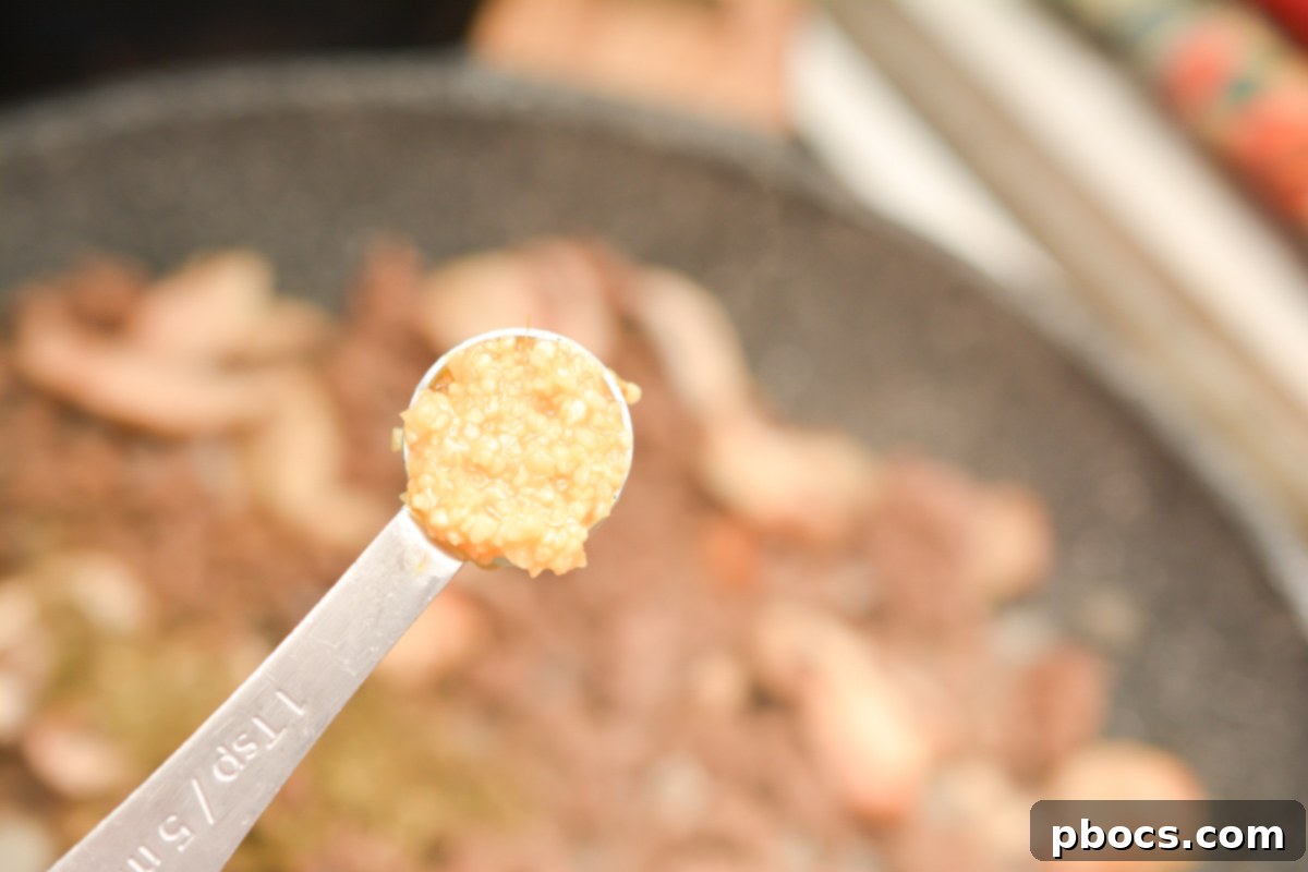 Ultimate Cheesy Keto Beef, Spinach & Mushroom Feast 10 Mushrooms added to ground beef and onions, sautéing in a skillet.