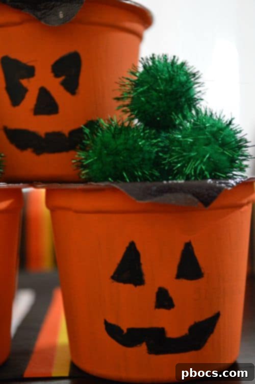 Close-up of a finished DIY Pumpkin Pudding Treat, highlighting the details of the painted face and pom-pom stem
